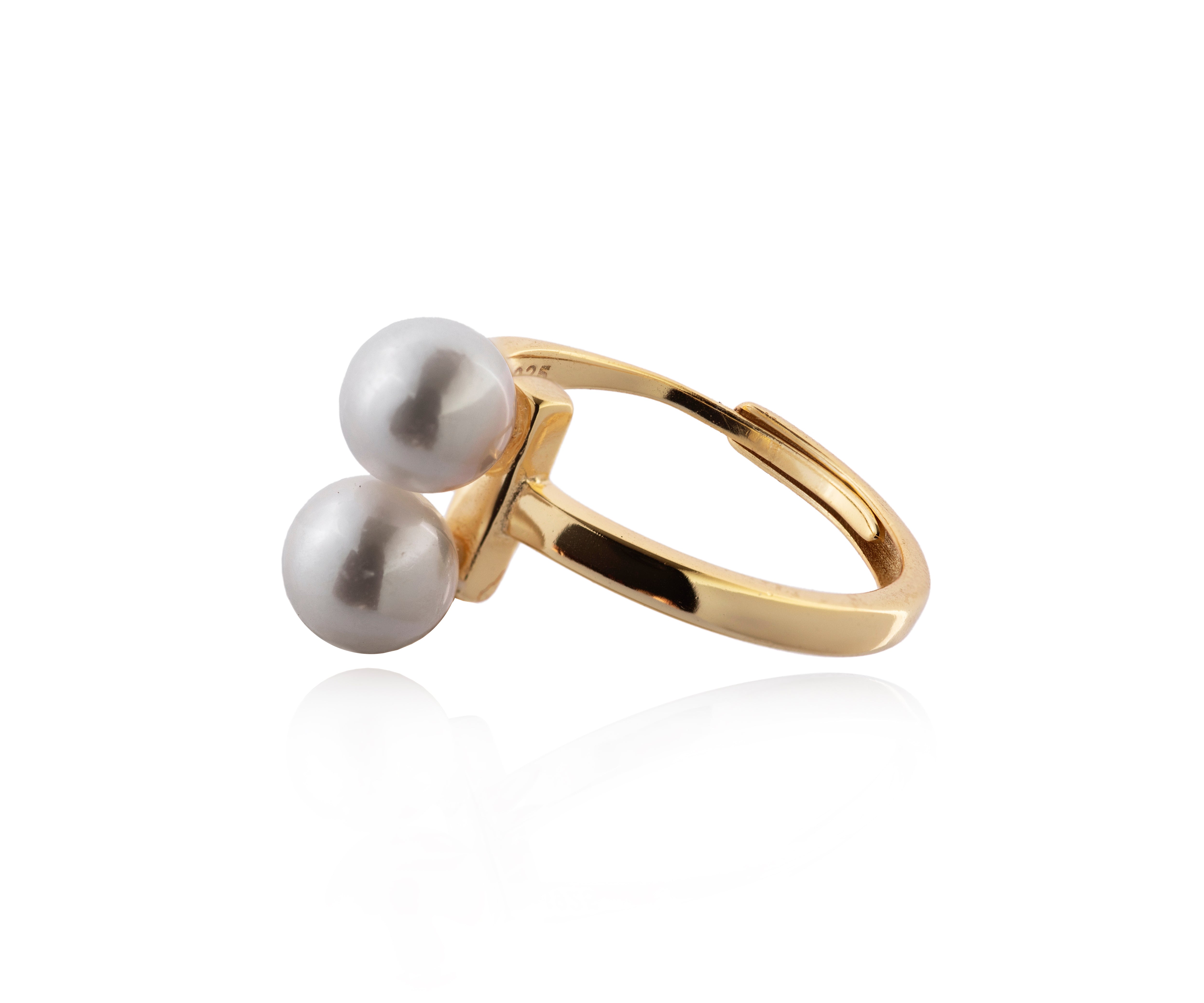 Anillo dorado con dos perlas gemelas.