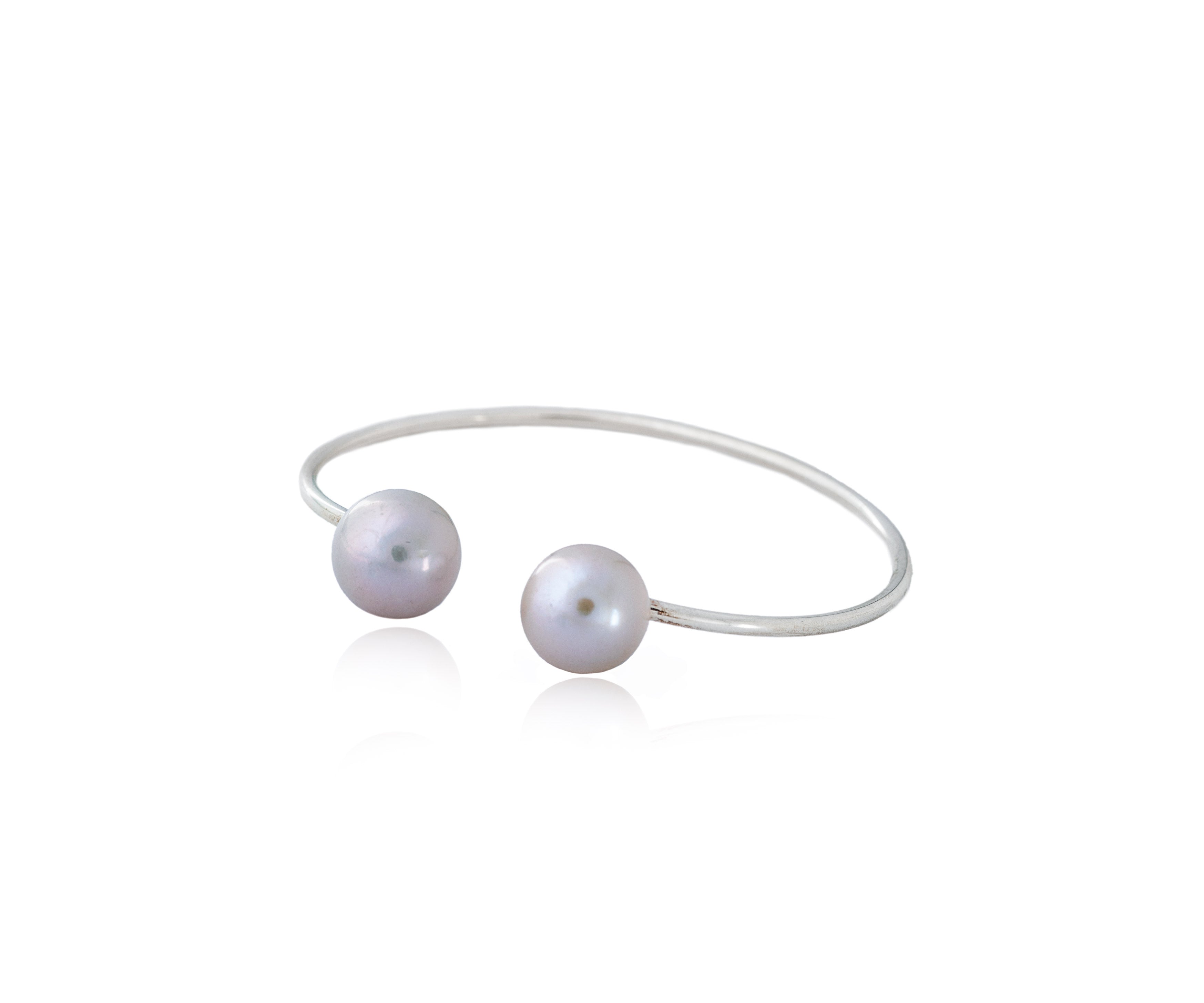 Pulsera rígida abierta con dos perlas enfrentadas.